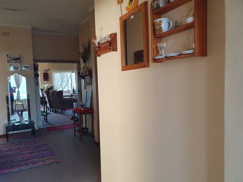 A view through a hallway leading into a living area, showing signs of ceiling wear and dated interior finishes.