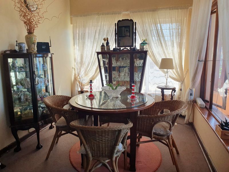 A dining room area featuring large windows that allow for natural light, finished with carpeted flooring.