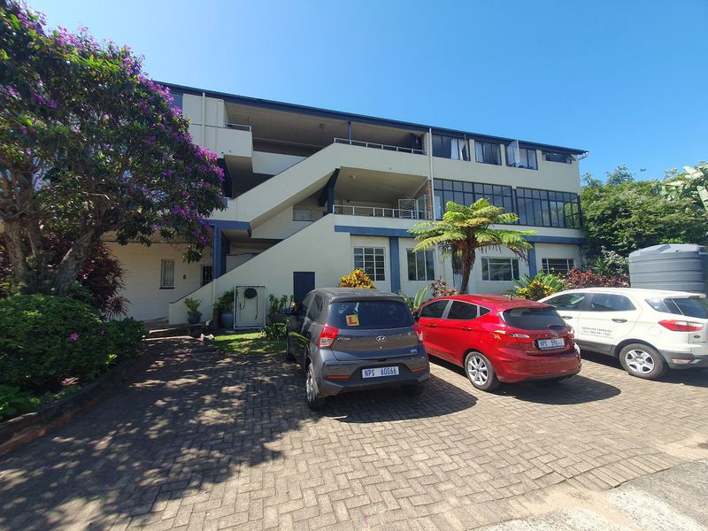 Front view of a multi-story apartment building featuring a paved driveway, external staircases, and private balconies.