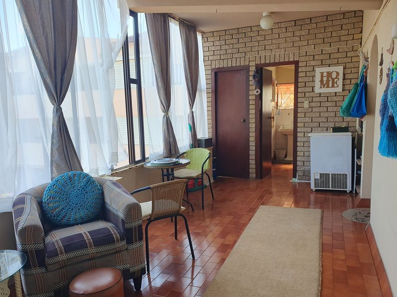 Enclosed balcony or sunroom featuring exposed brick walls, tiled flooring, and large windows providing ample natural light.