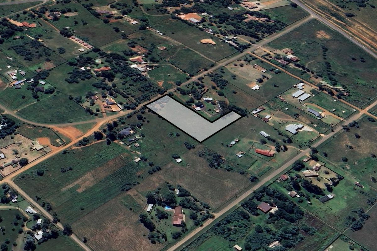 An aerial view of a vacant residential land plot situated within a rural or semi-rural neighborhood setting.