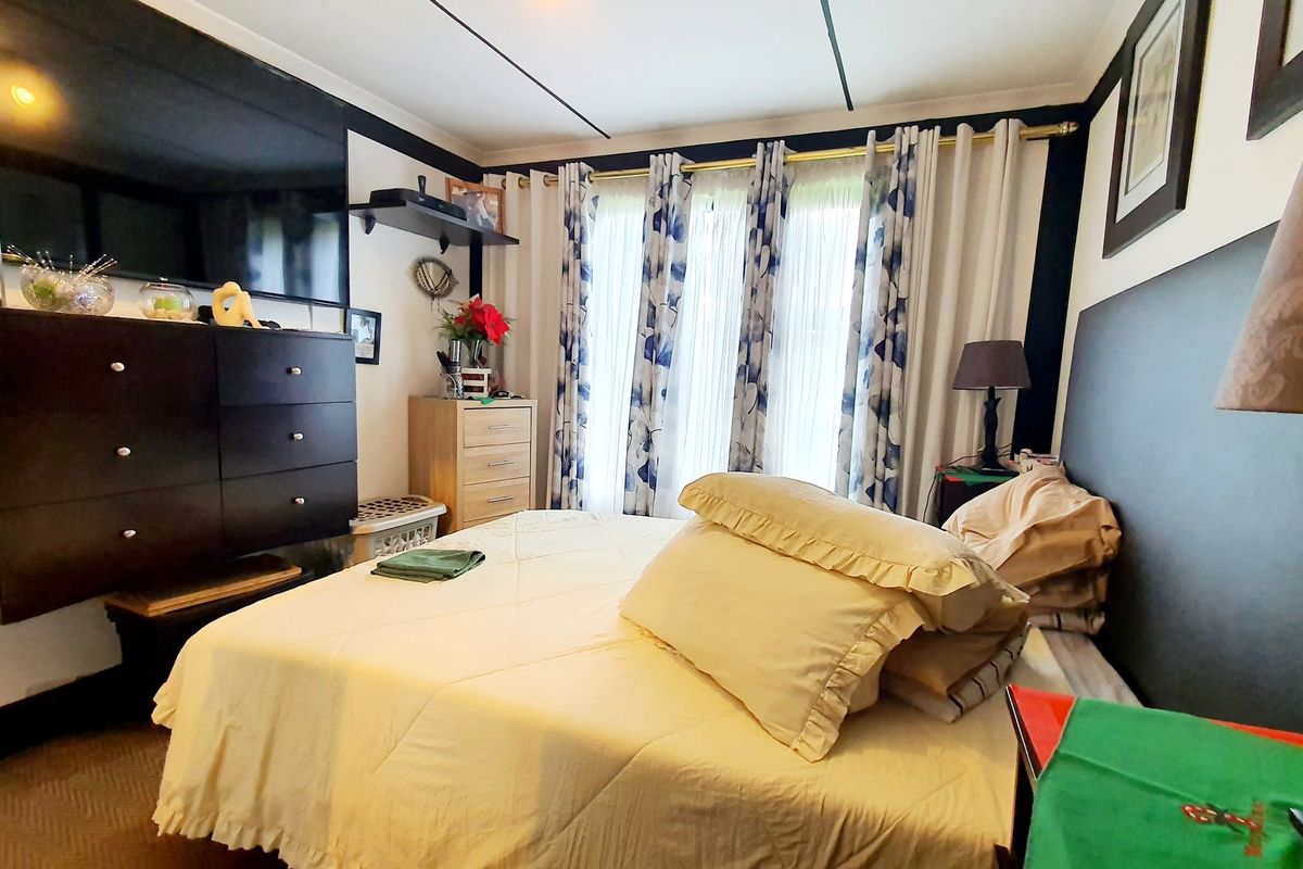 A bedroom featuring a built-in headboard and window treatments, offering a functional space with potential for modern updates.