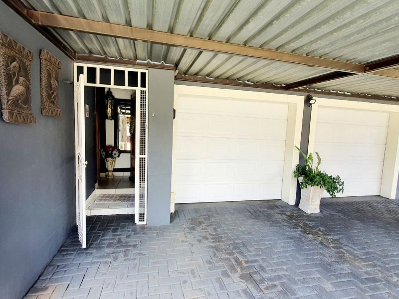 A covered double garage area featuring paved flooring, secure garage doors, and a direct entrance into the home.
