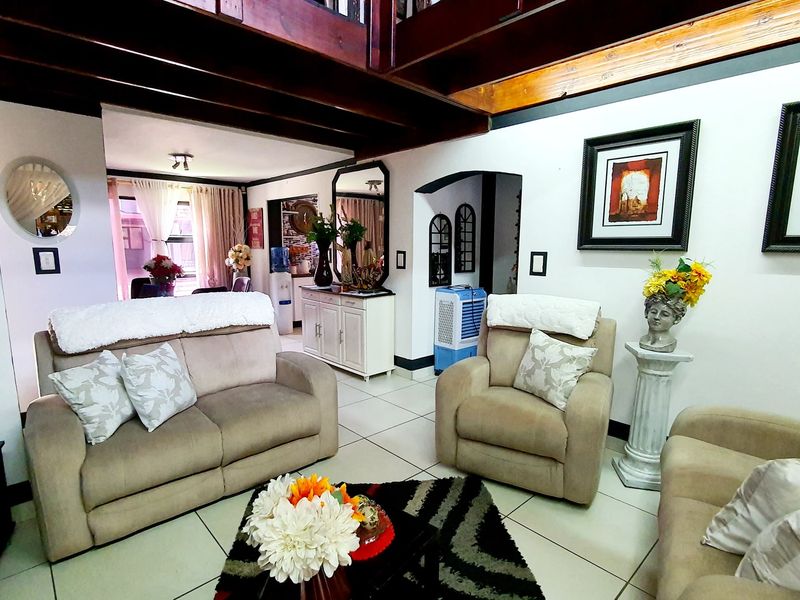 A comfortable living room featuring exposed timber ceiling beams, tiled flooring, and an open-plan layout leading to adjacent living spaces.