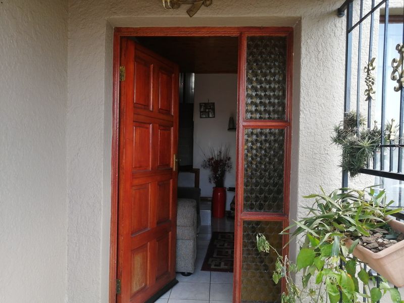 A traditional front entrance featuring a solid timber door with a decorative leaded glass sidelight and security gate access.