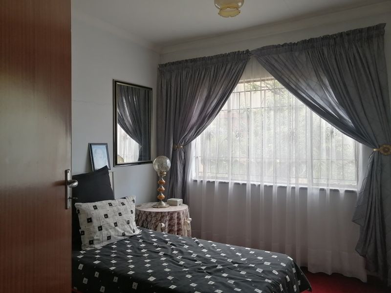 A functional bedroom featuring a window with security bars, ceiling cornice, and a central light fixture.