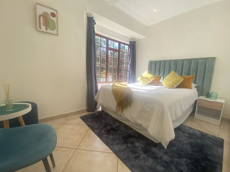 A well-lit bedroom featuring tiled flooring, recessed ceiling lights, and a large timber-framed window providing natural light.