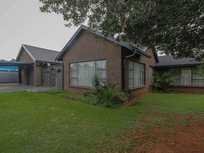 A well-maintained face-brick house featuring a tiled roof, large aluminium-framed windows, a paved driveway, and an attached double garage.