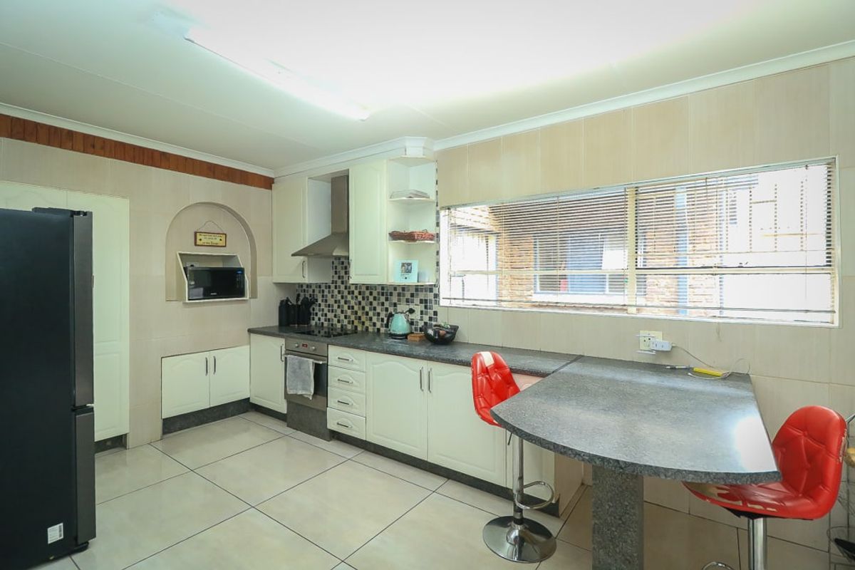 A functional kitchen featuring tiled flooring, built-in cabinetry, a breakfast bar, and integrated cooking appliances with a tiled backsplash.