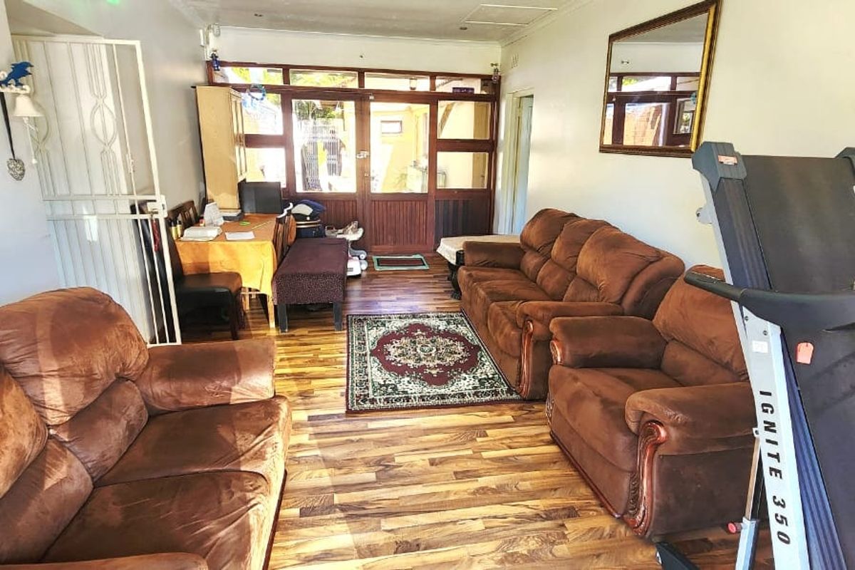 A living room featuring laminate flooring, recessed downlights, and a timber-framed glass door leading to an outdoor area.