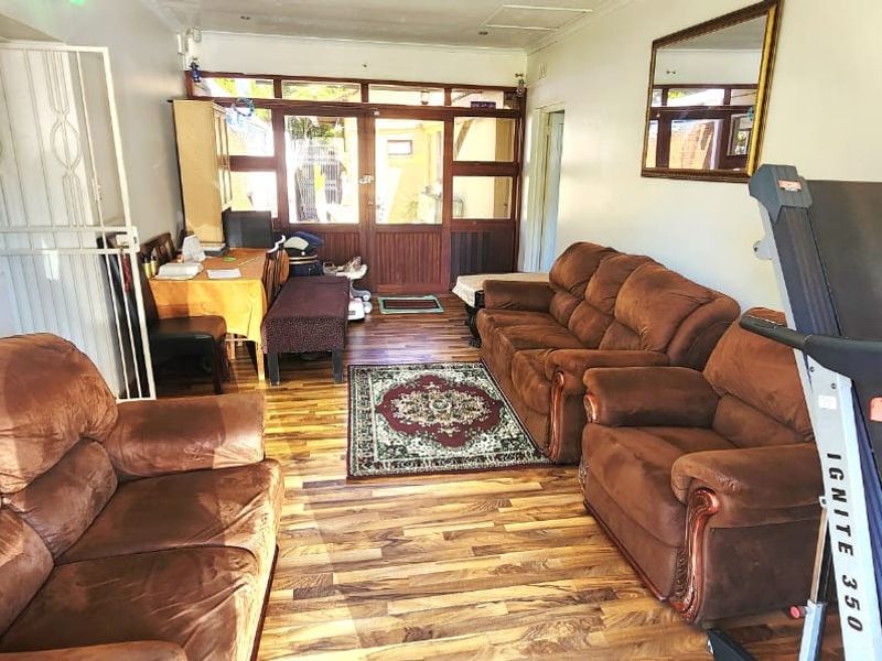 A living room featuring laminate flooring, recessed downlights, and a timber-framed glass door leading to an outdoor area.