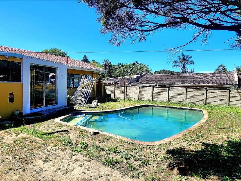 Rear exterior view featuring a swimming pool, paved patio area, and access to the home via sliding glass doors.
