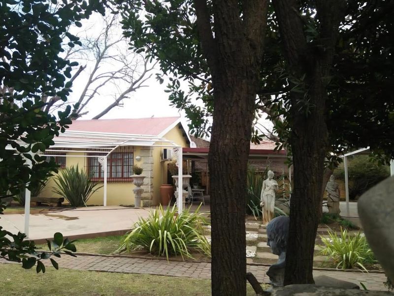Rear view of the property featuring a paved patio area, pergola structure, and established garden landscaping.