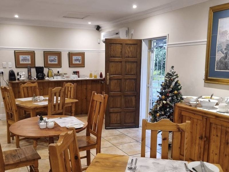 A dining area featuring tiled flooring, recessed lighting, and a split-system air conditioner, with direct access to an outdoor space through a timber door.
