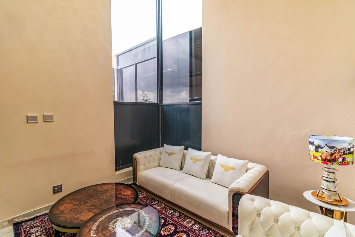 A bright living area featuring a striking full-height window that provides ample natural light and a modern architectural feel.