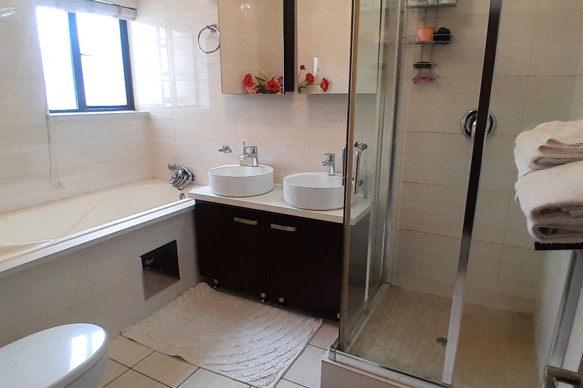 A functional bathroom featuring a double vanity with vessel sinks, a separate glass-enclosed shower, and a built-in bathtub with tiled finishes.