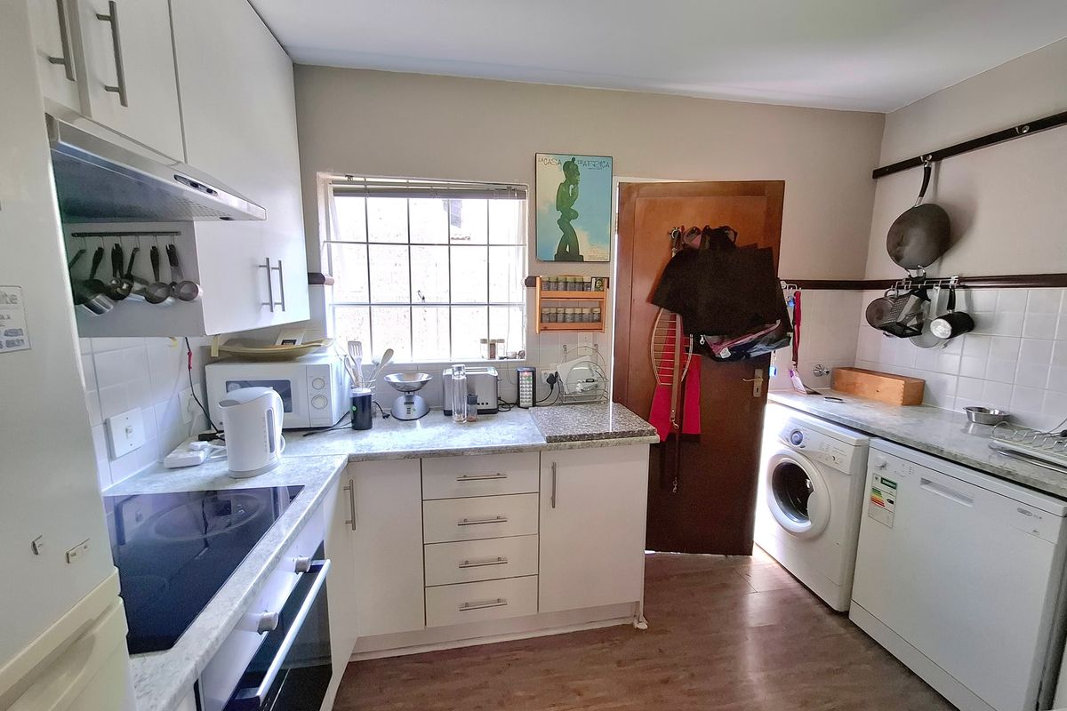 Functional kitchen featuring white cabinetry, laminate countertops, built-in oven, electric hob, and dedicated spaces for laundry and dishwasher appliances.