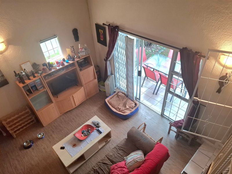 A high-angle view of a living room featuring laminate flooring, wall sconce lighting, and a sliding glass door leading to an outdoor patio area.