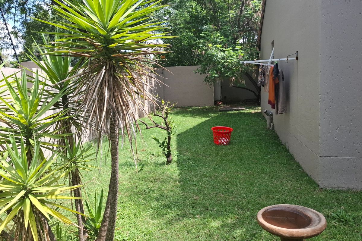 A private rear garden area featuring a lawn, boundary walls, and a wall-mounted clothesline.