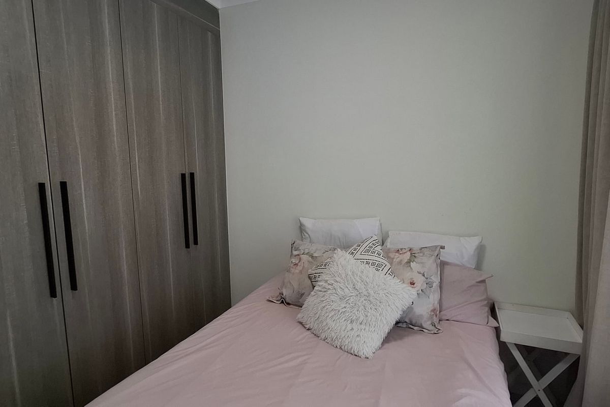 A well-maintained bedroom featuring modern built-in cupboards with sleek black handles and neutral wall finishes.