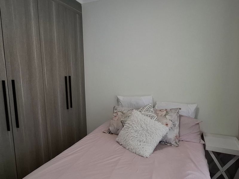 A well-maintained bedroom featuring modern built-in cupboards with sleek black handles and neutral wall finishes.
