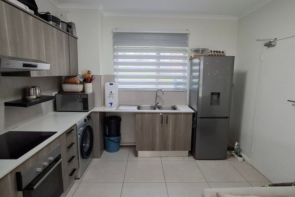 Modern kitchen featuring sleek grey cabinetry, integrated appliances, electric hob, oven, extractor fan, and tiled flooring with a functional layout.