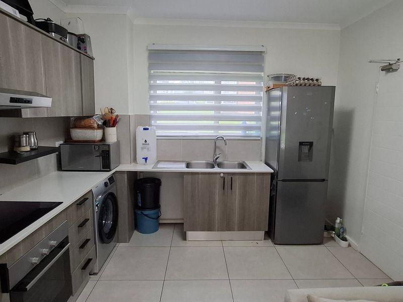 Modern kitchen featuring sleek grey cabinetry, integrated appliances, electric hob, oven, extractor fan, and tiled flooring with a functional layout.