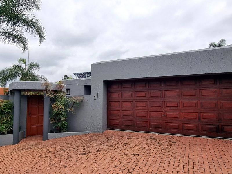 Front elevation of the cluster home featuring a double garage, paved driveway, and a private pedestrian entrance gate.
