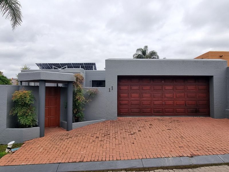 Front elevation of a cluster home featuring a paved driveway, double garage, and secure pedestrian entrance with boundary walling.
