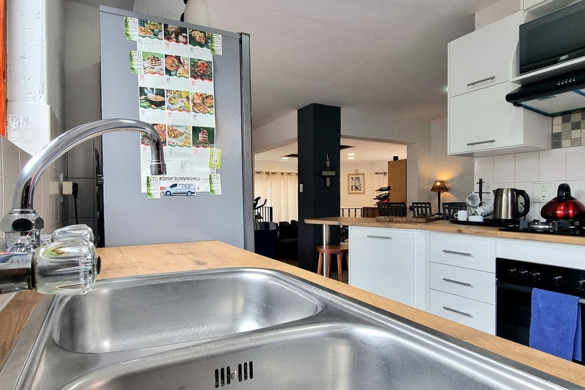 Modern kitchen featuring white cabinetry, laminate countertops, stainless steel double sink, built-in oven, gas hob, and extractor fan, with an open-plan layout.