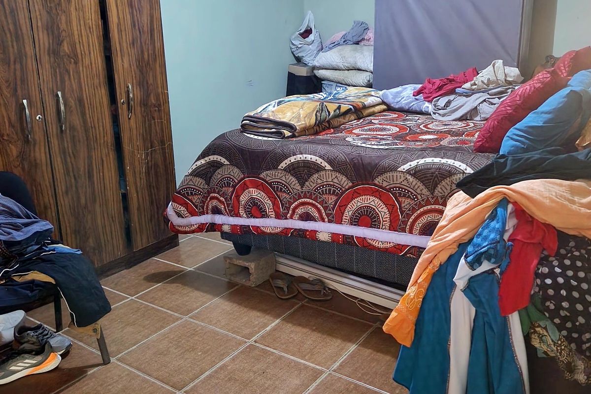 A bedroom featuring tiled flooring, a built-in wardrobe, and decorative ceiling cornicing, currently requiring cosmetic updates and maintenance to the walls and ceiling.