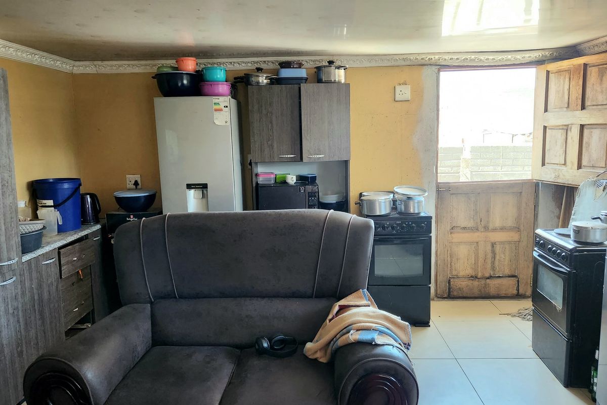 A functional kitchen area featuring tiled floors, built-in cabinetry, and a freestanding stove, with direct access to an exterior door.