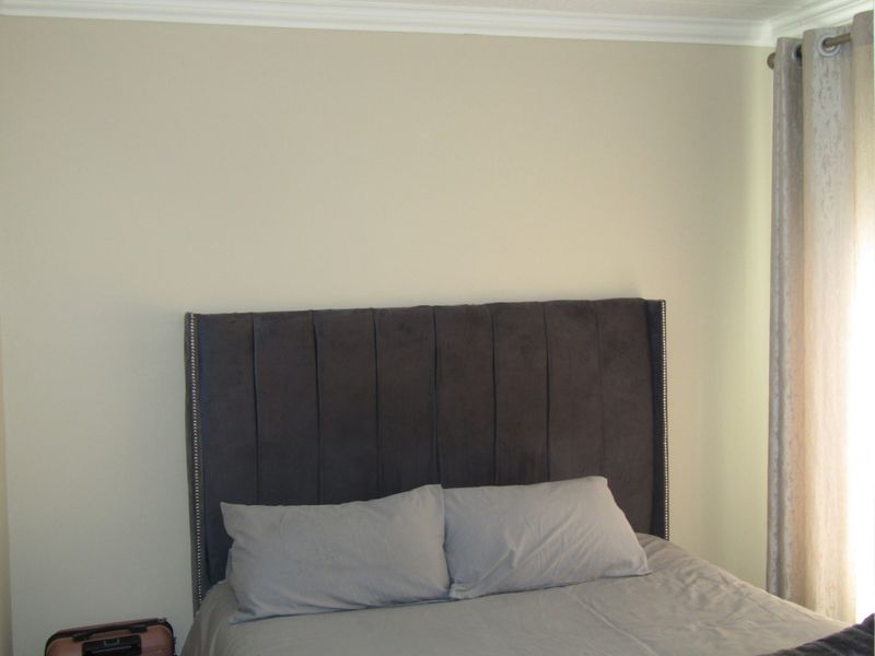 A neutrally painted bedroom featuring decorative coving and window treatments.