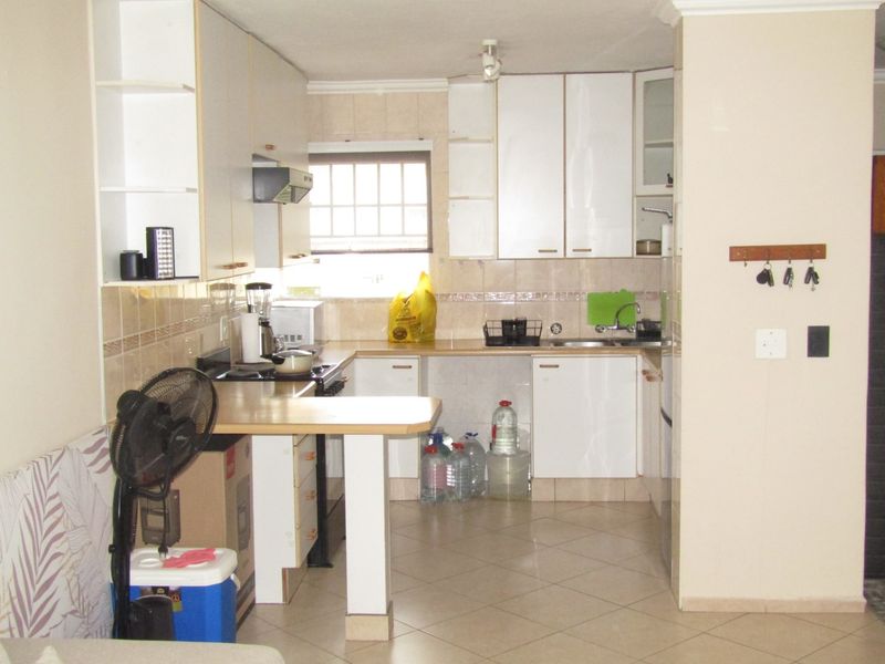 A functional kitchen featuring white built-in cabinetry, laminate countertops, a tiled backsplash, and ceramic floor tiles, offering a practical layout for daily use.