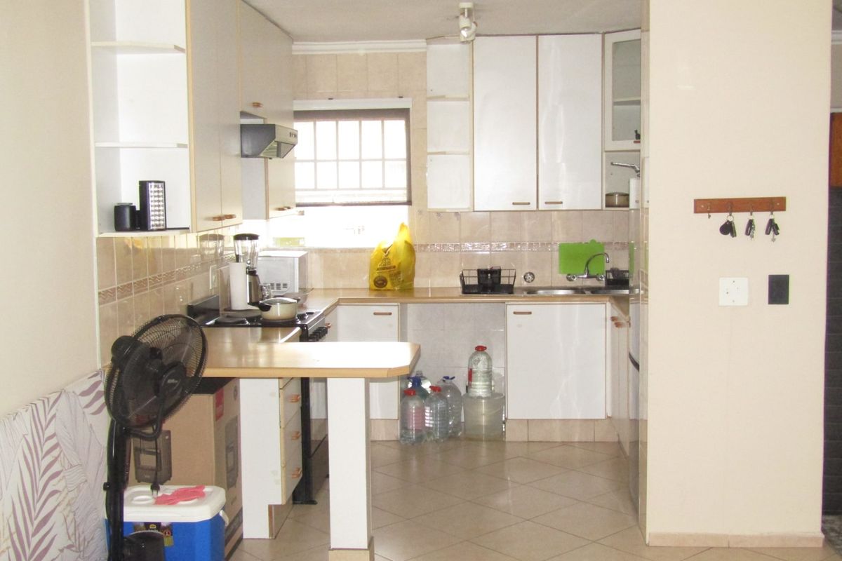 A functional kitchen featuring white built-in cabinetry, laminate countertops, a tiled backsplash, and ceramic floor tiles, offering a practical layout for daily use.