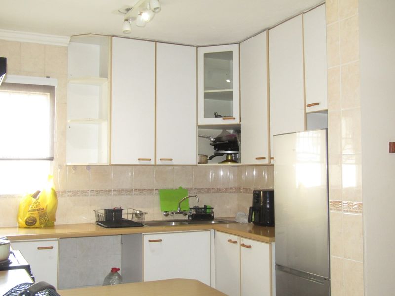 A functional kitchen featuring white cabinetry, laminate countertops, and a tiled backsplash, providing a practical workspace with integrated storage solutions.