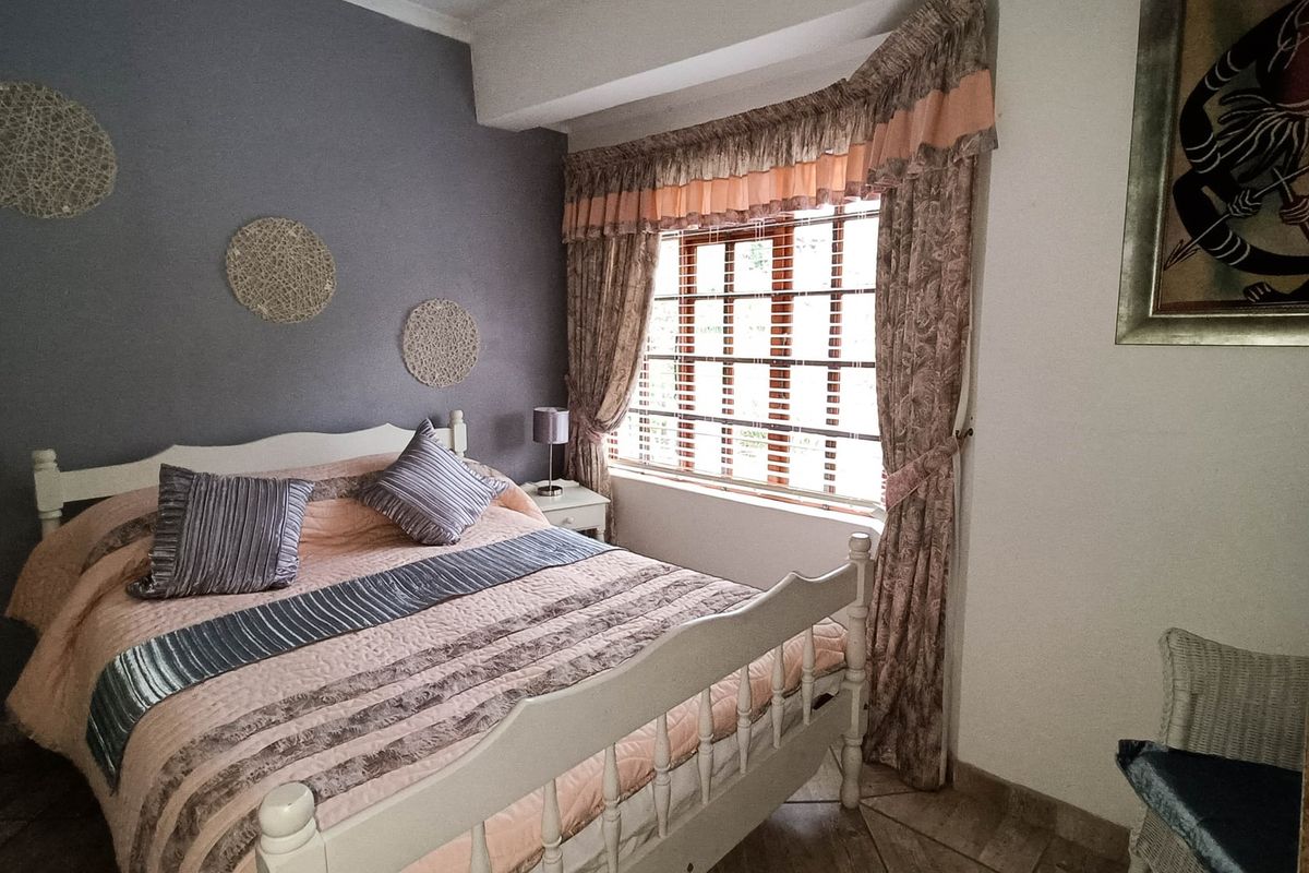 A cozy bedroom featuring tiled flooring and a window fitted with security bars, offering a functional and comfortable living space.