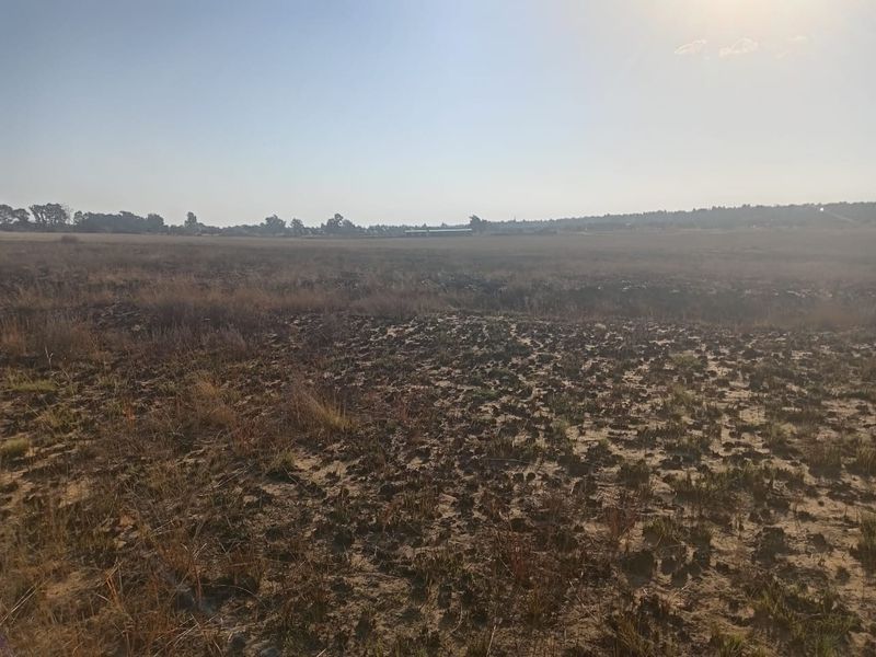 A wide-angle view of a vacant residential plot featuring natural dry vegetation and open landscape, suitable for future development.
