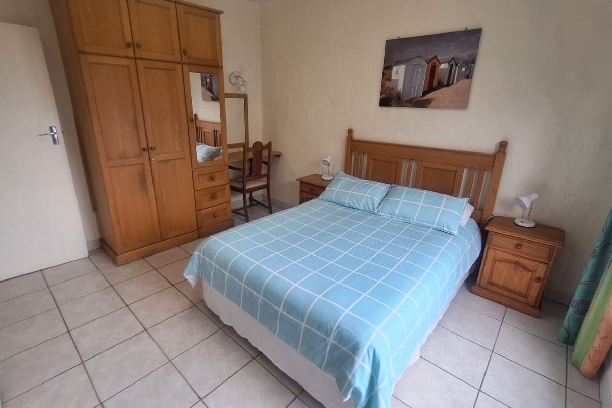 A functional bedroom featuring tiled flooring and a built-in wooden wardrobe, offering a simple and practical living space.