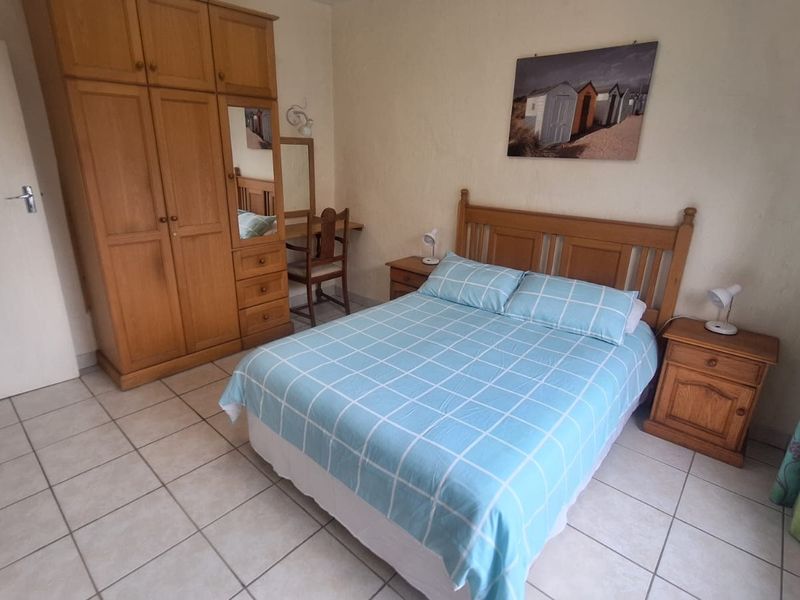 A functional bedroom featuring tiled flooring and a built-in wooden wardrobe, offering a simple and practical living space.