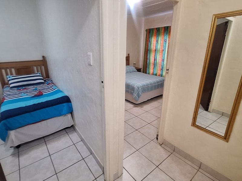 A view from the hallway looking into two bedrooms, featuring neutral tiled flooring and standard internal door frames.