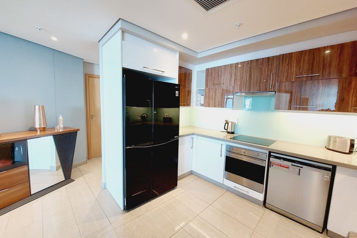Modern kitchen featuring high-gloss cabinetry, integrated appliances including an oven and dishwasher, sleek tiled flooring, and recessed ceiling lighting.