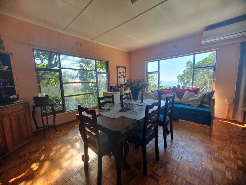A dining room featuring parquet flooring, large windows with natural light, and a wall-mounted air conditioning unit.