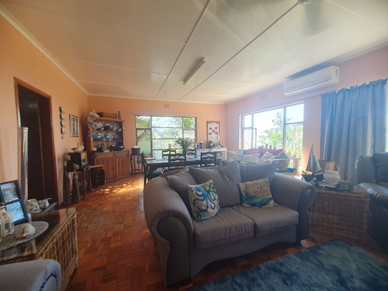 Spacious open-plan living and dining area featuring classic parquet flooring, large windows for natural light, and a wall-mounted air conditioning unit.