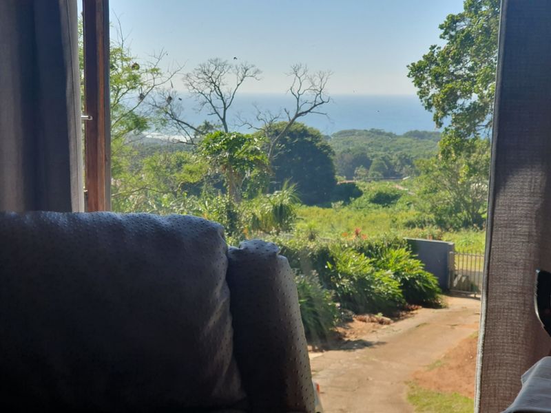 A scenic view of the surrounding landscape and ocean captured through a timber-framed window.
