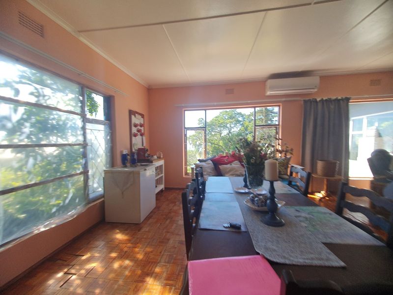 Dining room featuring parquet flooring, large windows providing natural light, and a wall-mounted air conditioning unit.