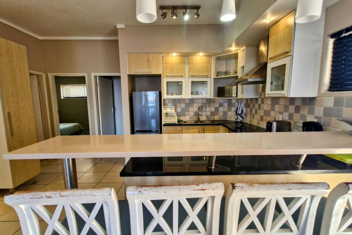 Functional kitchen featuring a stone breakfast bar, tiled backsplash, and ample built-in cabinetry, providing a practical layout for cooking and casual dining.