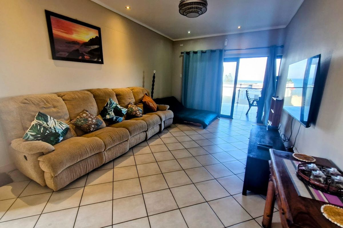 A comfortable living room featuring ceramic floor tiles, recessed lighting, and direct access to a balcony with ocean views.