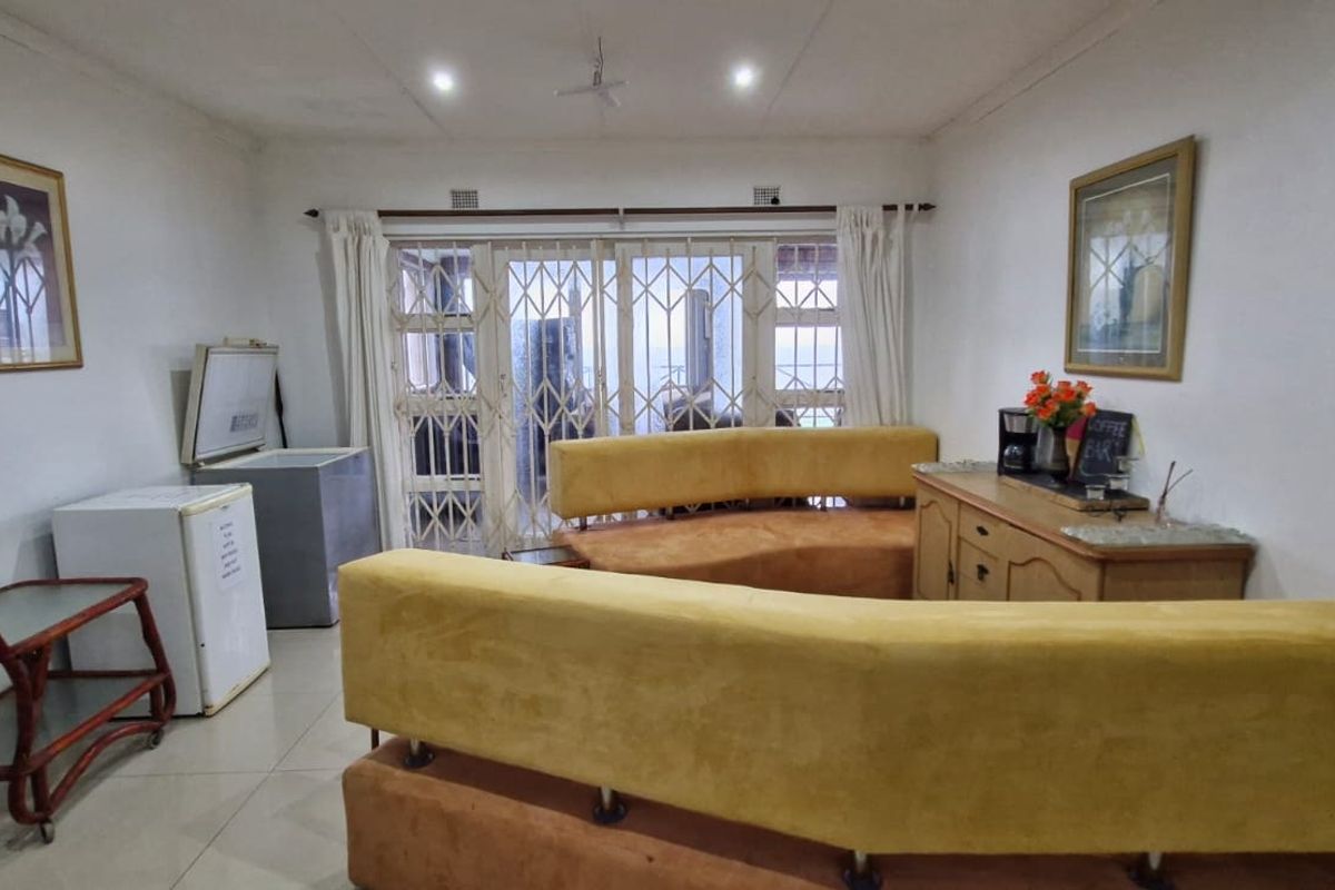A living room featuring tiled flooring, recessed lighting, and a sliding glass door with a security gate leading to the exterior.