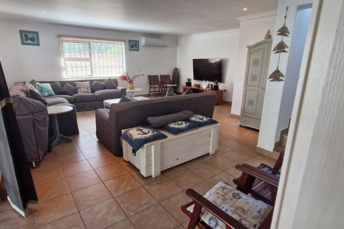 Spacious living room featuring tiled flooring, recessed downlighting, and a wall-mounted air conditioning unit.